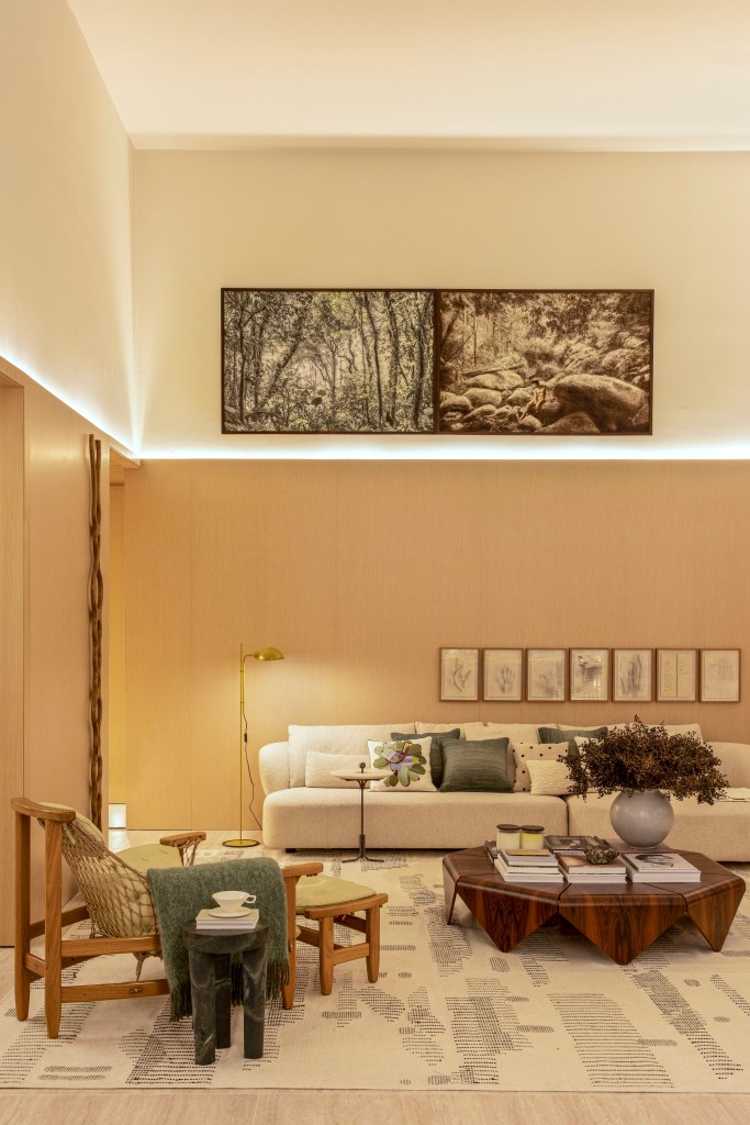 Quiet luxury e feng shui indiano marcam este loft de 120 m², Projeto de Bianca Da Hora Arquitetura para a CASACOR SP 2023. Na foto, sala de estar com meia-parede, quadros, estante e sofá.