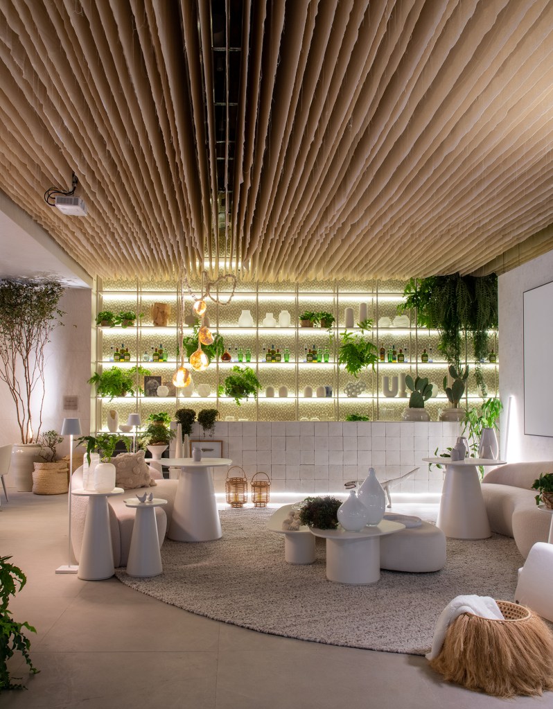 Restaurante grego em SP é inspirado na arquitetura de Mykonos. Projeto de Carla Felippi para a CASACOR São Paulo 2023. Na foto, bar com estante, cortinas no teto e móveis curvos.