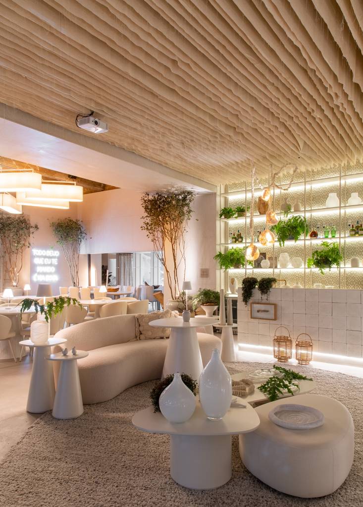 Restaurante grego em SP é inspirado na arquitetura de Mykonos. Projeto de Carla Felippi para a CASACOR São Paulo 2023. Na foto, bar com estante, cortinas no teto e móveis curvos.