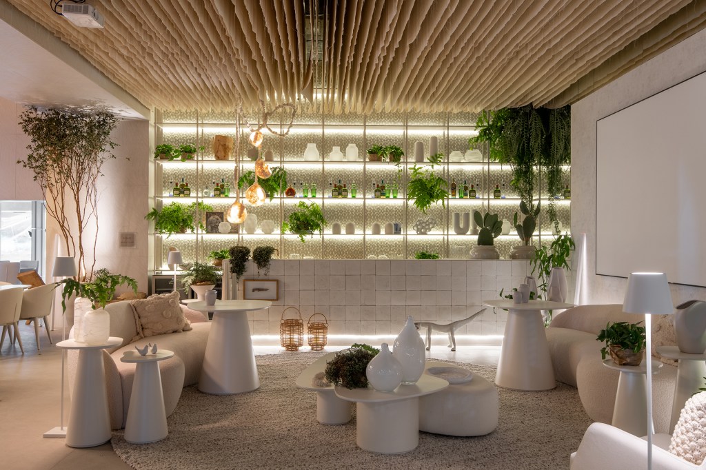 Restaurante grego em SP é inspirado na arquitetura de Mykonos. Projeto de Carla Felippi para a CASACOR São Paulo 2023. Na foto, bar com estante, cortinas no teto e móveis curvos.