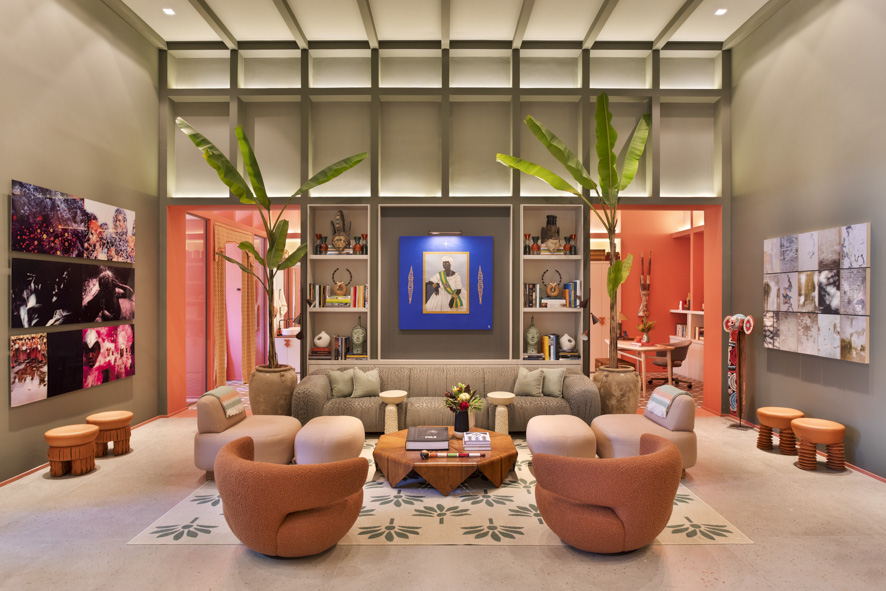 ritmo-alegria-samba-inspiram-casa-paleta-de-cores-vibrante-marcelo-salum-casacor-sp-2023-04 Sala de estar com sofá cinza, poltronas coral e parede verde com pé-direito alto.