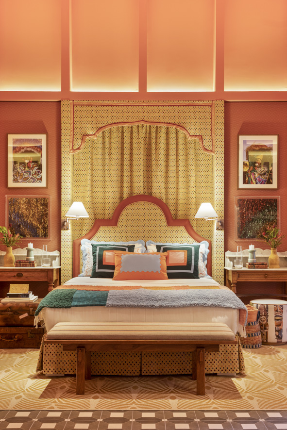 Quarto com cabeceira estampada, cama de casal com roupa de cama colorida e parede coral.