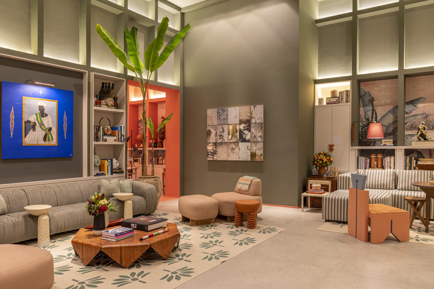 ritmo-alegria-samba-inspiram-casa-paleta-de-cores-vibrante-marcelo-salum-casacor-sp-2023-07 Sala de estar com pé-direito alto, parede verde, sofá baixo, poltrona e mesa de centro de madeira.