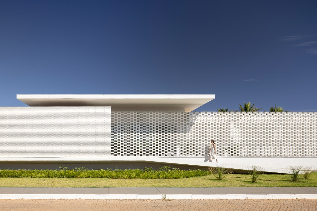 Tijolos vazados brancos compõem a fachada desta casa de 600 m² em Brasília. Projeto de Bloco Arquitetos. Na foto, fachada vazada com blocos vazados e jardim.