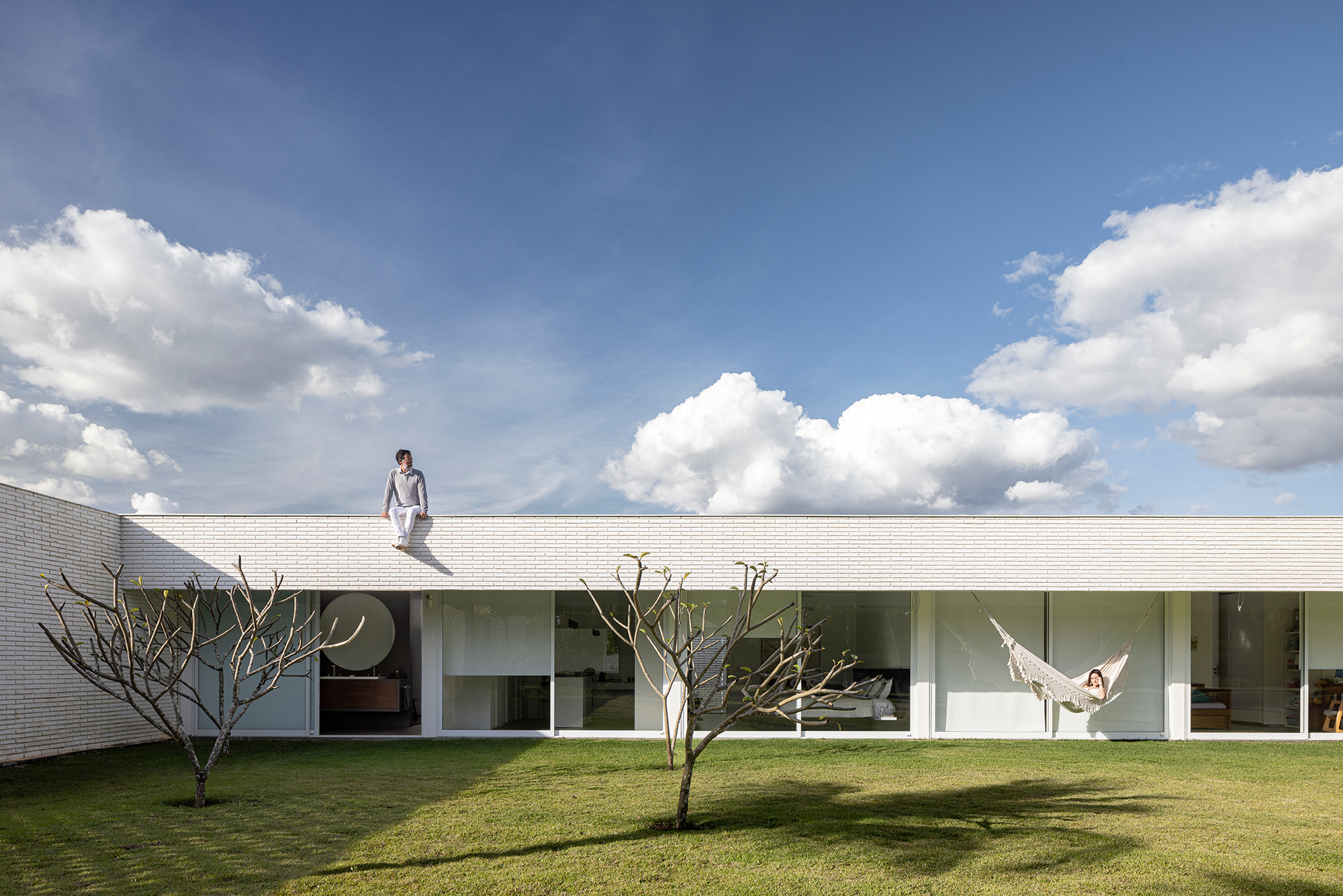 Tijolos vazados brancos compõem a fachada desta casa de 600 m² em Brasília. Projeto de Bloco Arquitetos. Na foto, jardim com varanda dos ambientes sociais.