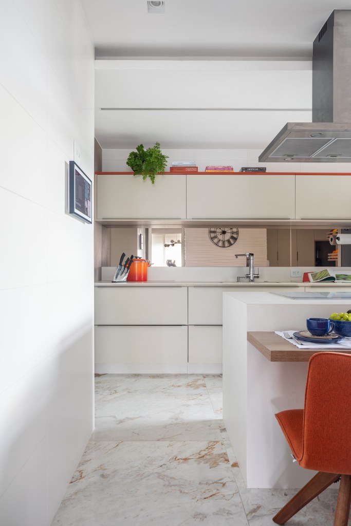 Cozinha integrada com marcenaria branca e piso marmorizado.