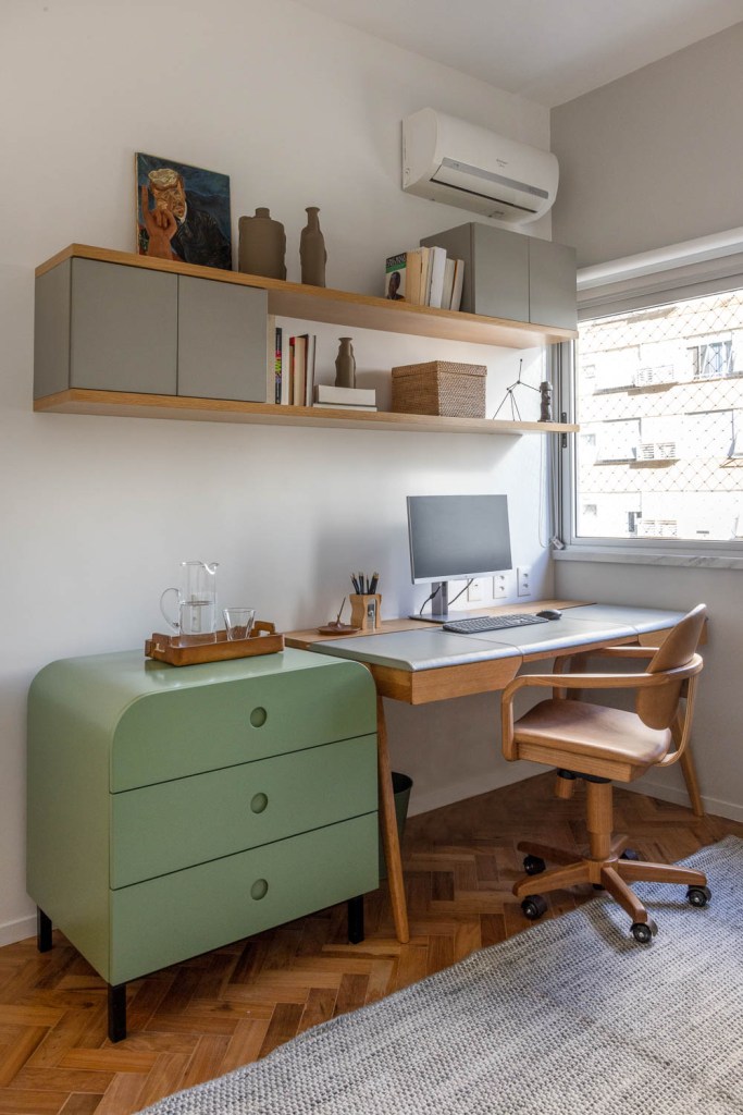 Home office com bancada de madeira e gaveteiro verde;