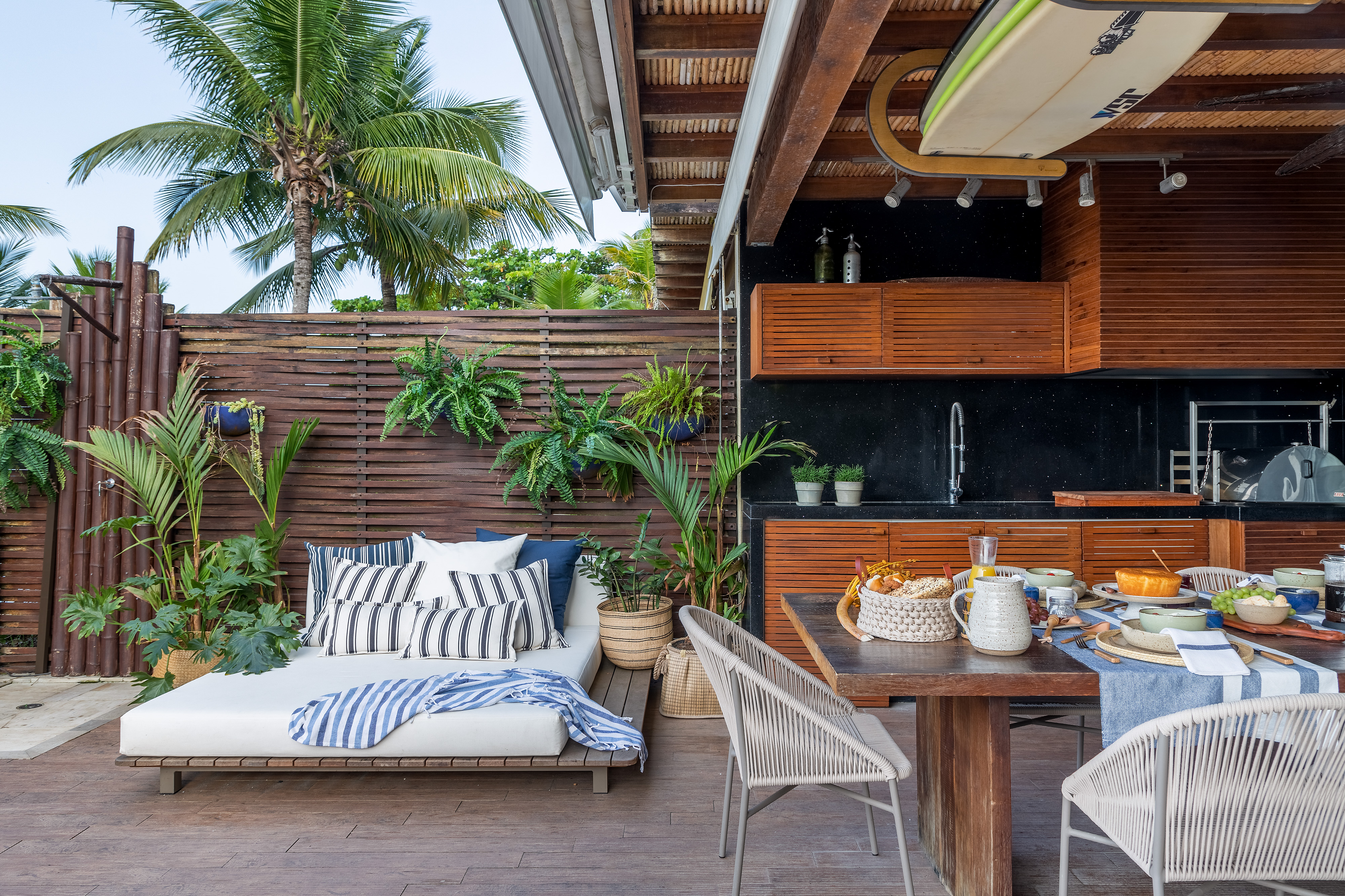 A vista da sala desta casa de praia é o mar de Juquehy. Projeto de Beatriz Quinelato. Na foto, varanda gourmet com churrasqueira, daybed e móveis de madeira.