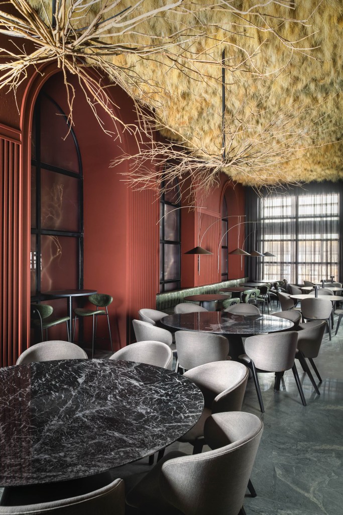 50 mil hastes de aspargos secos adornam o teto deste restaurante. Projeto de Renan Altera para a CASACOR SP 2023. Na foto, teto de aspargo, mesa preta e sofá verde.