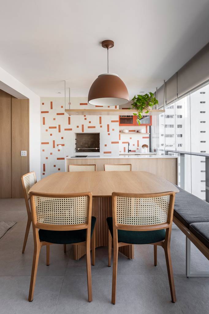 Apartamento ganha canto zen com rede de balanço e chão de pedriscos. Projeto de Interni Arquitetura. Na foto, varanda gourmet com banco, ladrilho hidraulico e cadeira de palhinha.