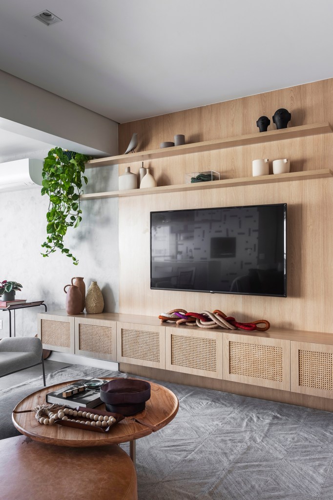 Apartamento ganha canto zen com rede de balanço e chão de pedriscos. Projeto de Interni Arquitetura. Na foto, sala de estar com painel de tv, tapete e mesas.