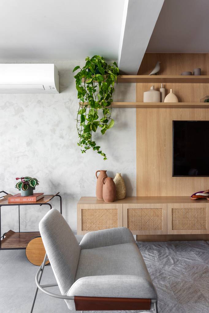 Apartamento ganha canto zen com rede de balanço e chão de pedriscos. Projeto de Interni Arquitetura. Na foto, sala com painel de tv, tapete e pufes.