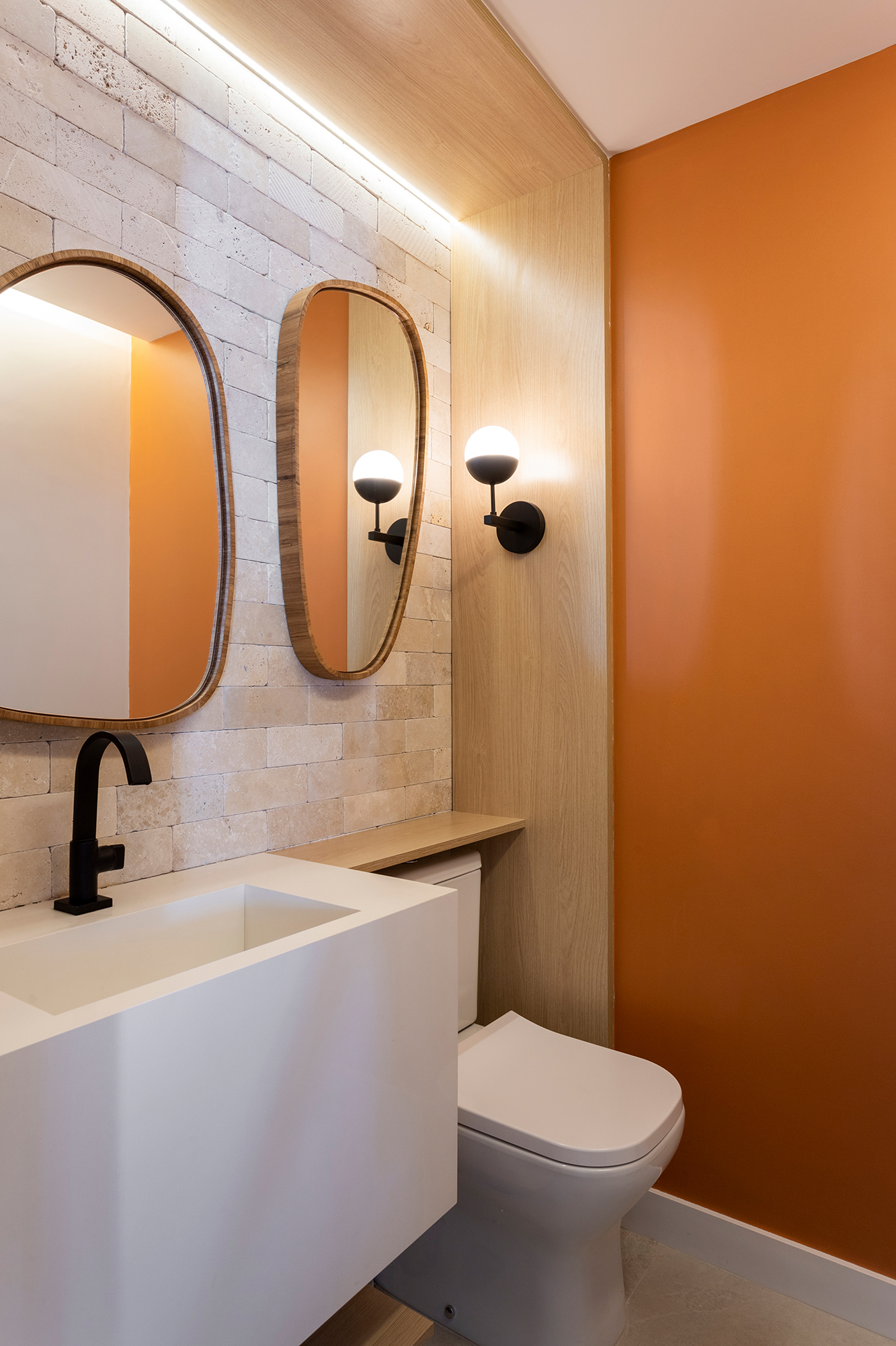 Apartamento ganha canto zen com rede de balanço e chão de pedriscos. Projeto de Interni Arquitetura. Na foto, lavabo com parede de tijolo e parede laranja.