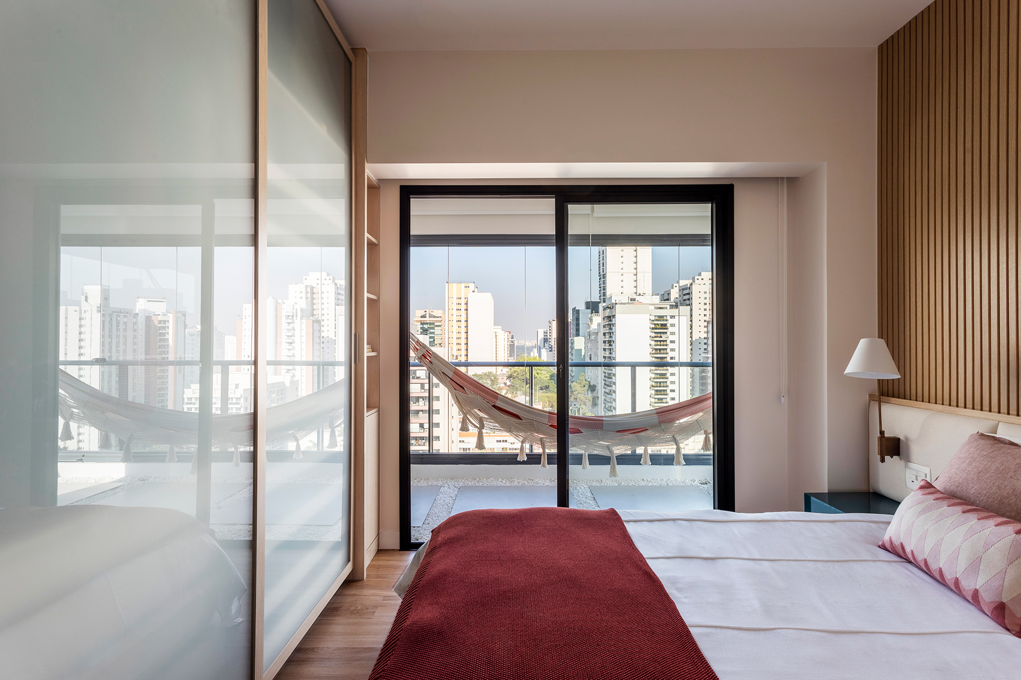 Apartamento ganha canto zen com rede de balanço e chão de pedriscos. Projeto de Interni Arquitetura. Na foto, quarto com varanda com rede e parede ripada.