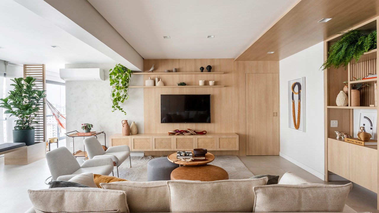 Apartamento ganha canto zen com rede de balanço e chão de pedriscos. Projeto de Interni Arquitetura. Na foto, sala de estar com tv, marcenaria, e sofá.