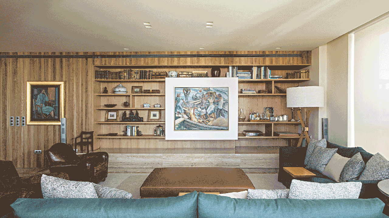 Sala de estar com estante de madeira com quadro que desliza escondendo a tv.