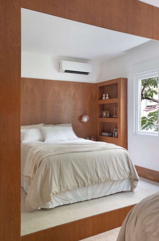 Projeto de Bianca Da Hora. Na foto, quarto com cama de casal e parede revestida de madeira.