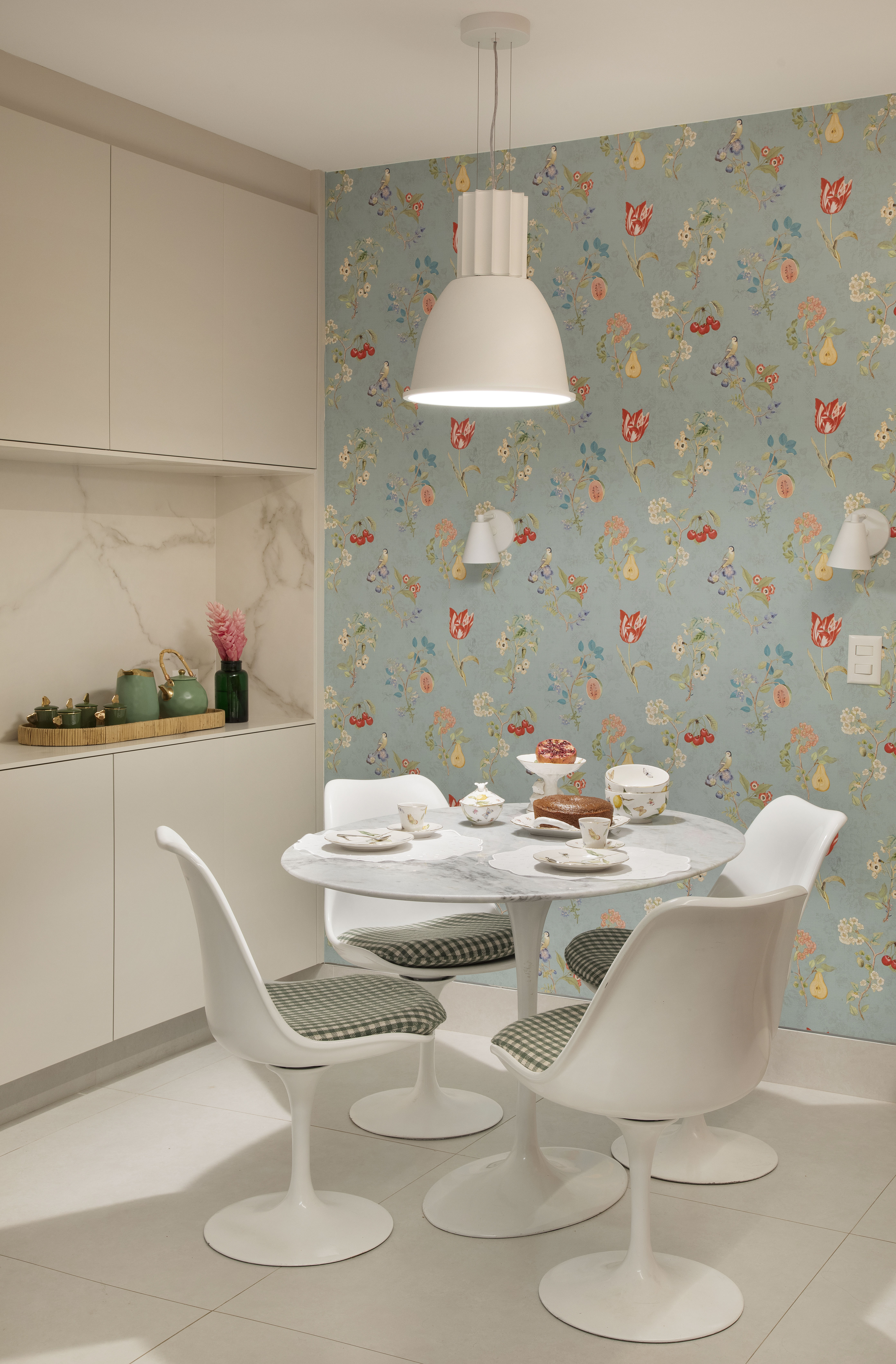 Projeto de Bianca Da Hora. Na foto, cozinha com copa, mesa redonda branca e papel de parede floral.