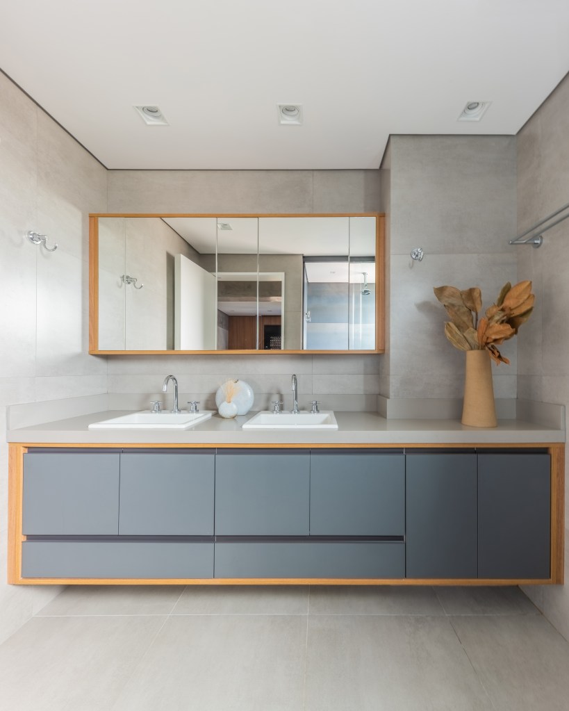 Projeto de Pietro Terlizzi. Na foto, banheiro com marcenaria cinza e revestimento de porcelanato no padrão cimento queimado.