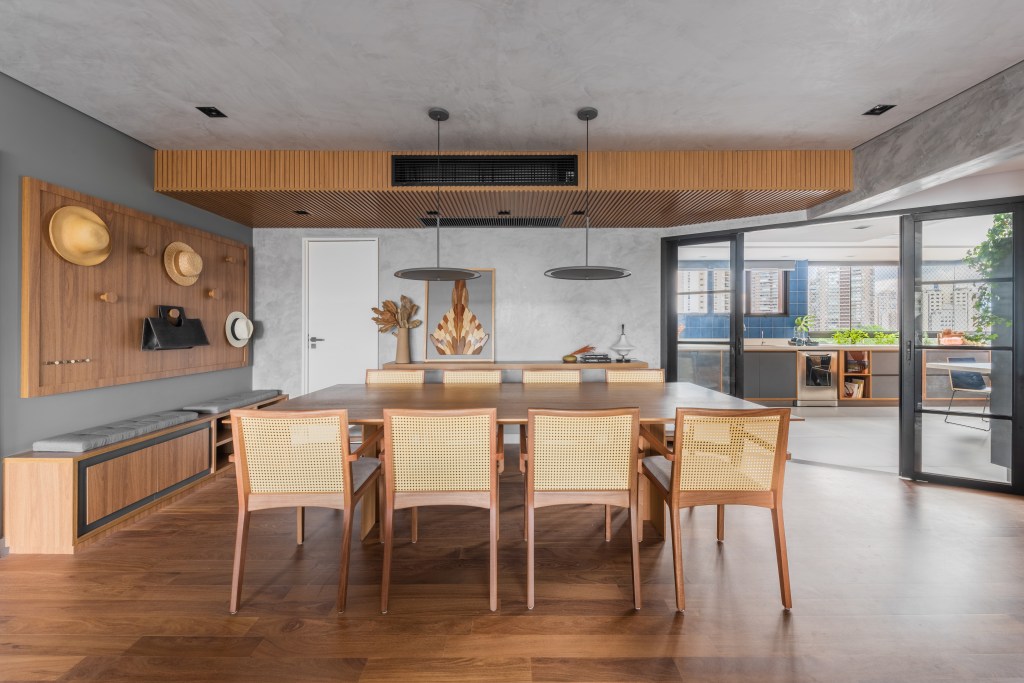 Projeto de Pietro Terlizzi. Na foto, sala de jantar com mesa de madeira e bancada de madeira suspensa na lateral.