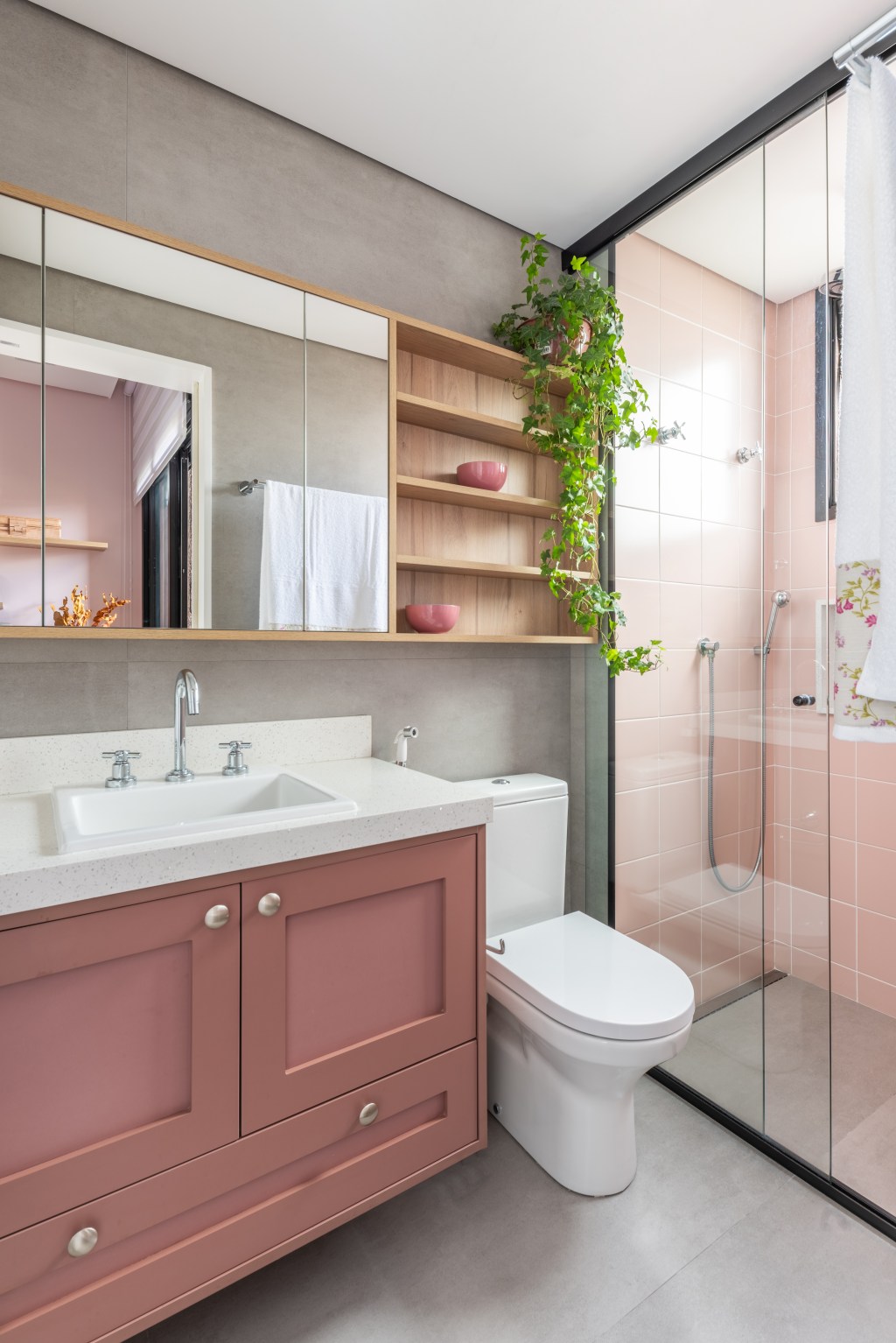 Projeto de Pietro Terlizzi. Na foto, banheiro com marcenaria rosa, armários aéreos espelhados, box de vidro, armário rosa, box revestido de azulejos rosa.