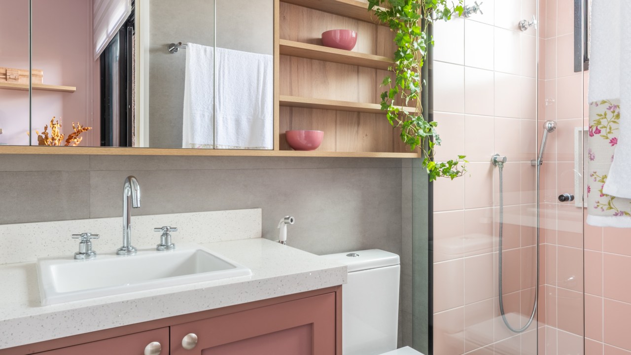 Projeto de Pietro Terlizzi. Na foto, banheiro com marcenaria rosa, armários aéreos espelhados, box de vidro, armário rosa, box revestido de azulejos rosa.