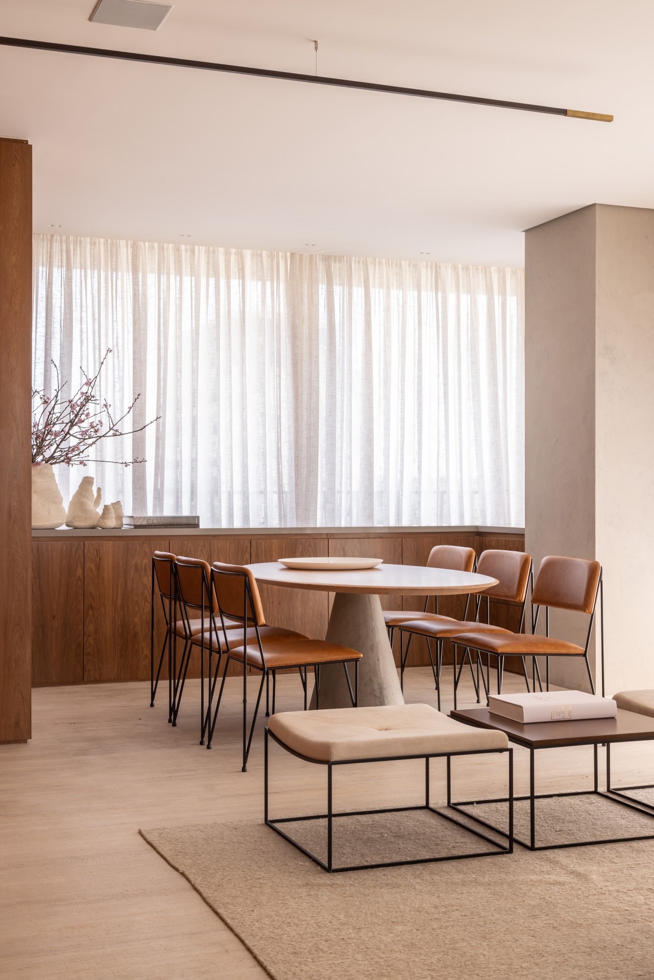 Projeto de Denise Polverini e Fernanda Villefort. Na foto, sala de jantar com tapete bege, mesa oval, cadeiras em couro, buffet de madeira e cortinas.
