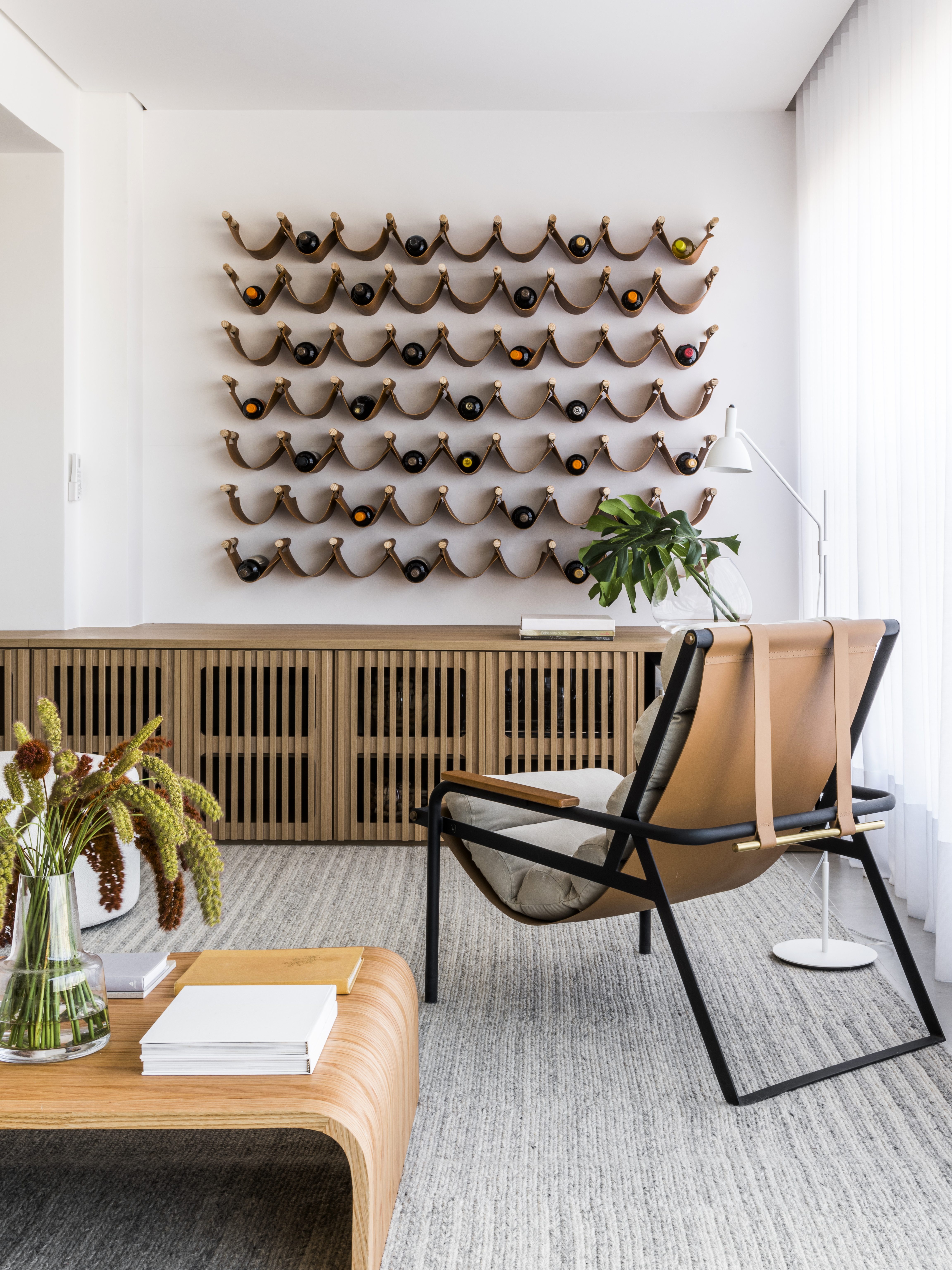 Projeto de Ticiane Lima. Na foto, sala de estar com varanda integrada, buffet de madeira, adega com fitas de couro.