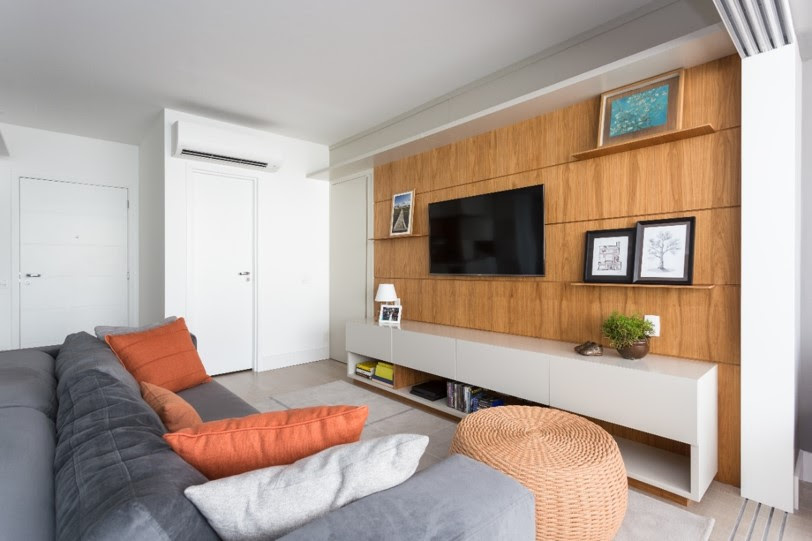 Sala de estar com sofá cinza e parede revestida com painel de madeira.