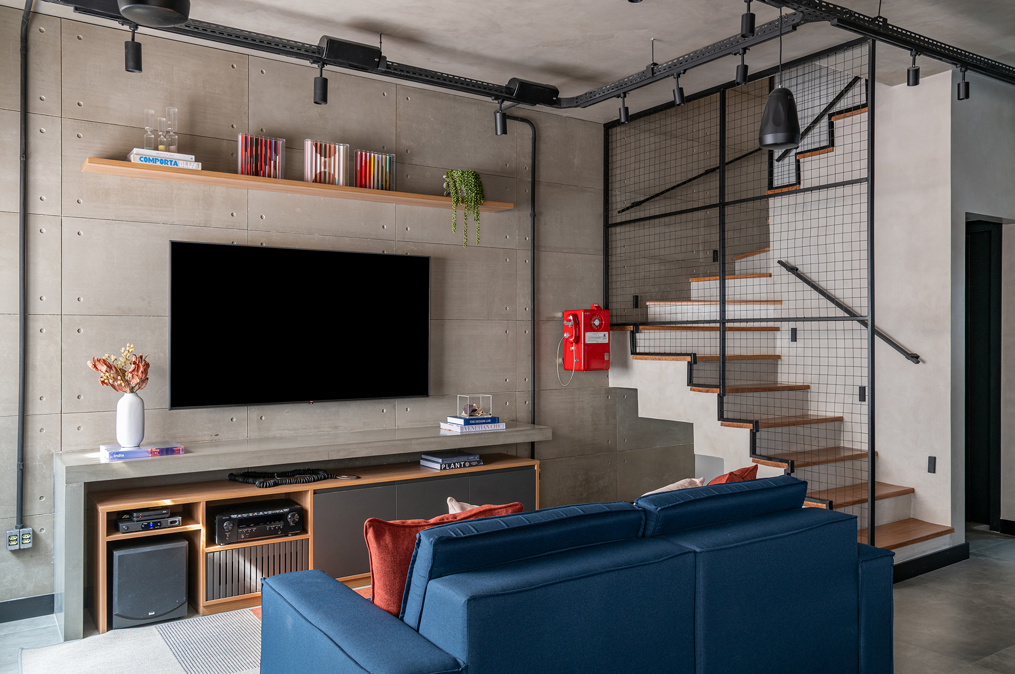 Casa de 200 m² ganha estilo industrial moderno, iluminação aparente e monocromia. Projeto de Dani Espírito Santo. Na foto, escada com guarda-corpo de serralheria. Sala de TV com sofá azul.