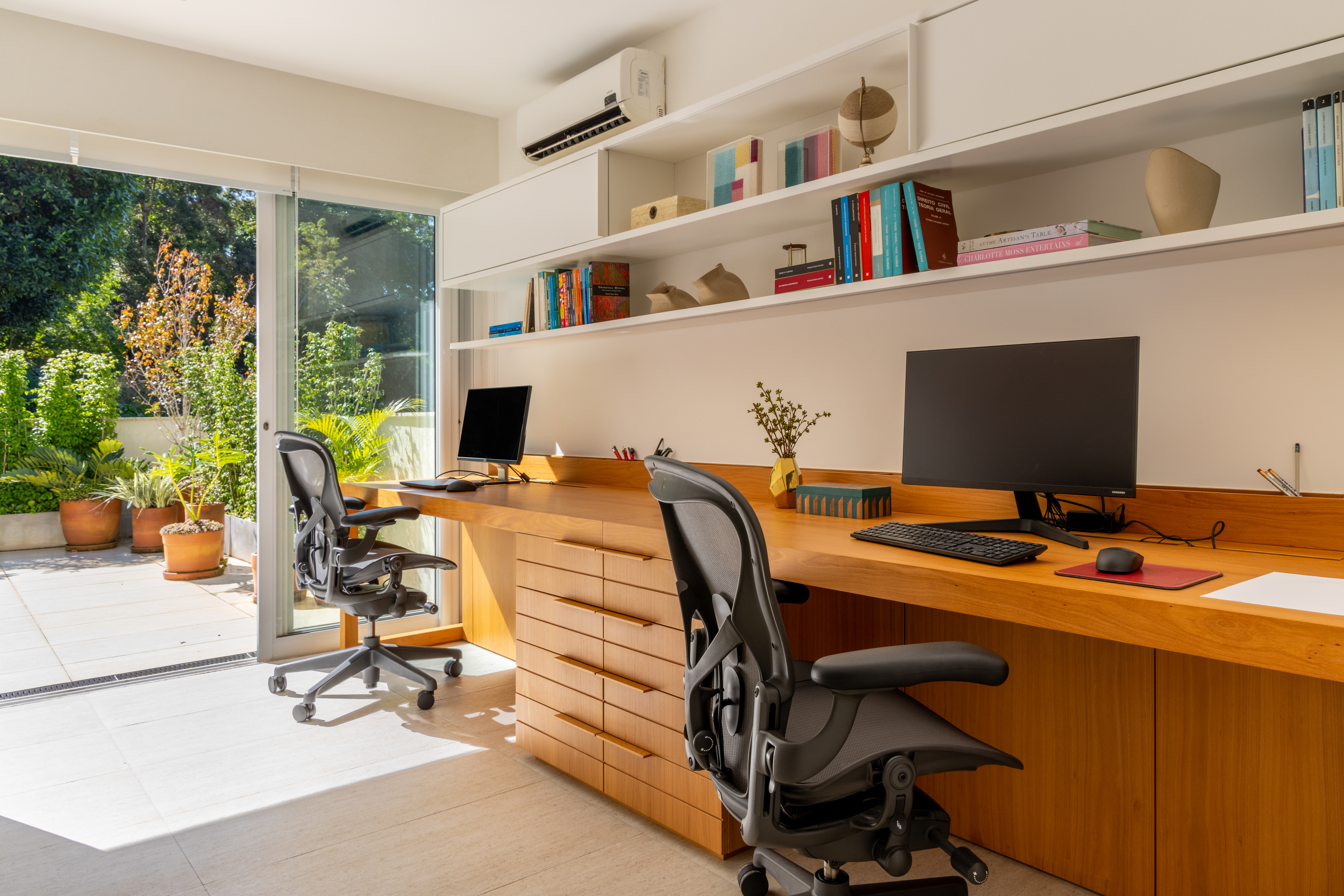 Projeto de Manuela Santos. Na foto, home office duplo com bancada de madeira e prateleiras brancas.