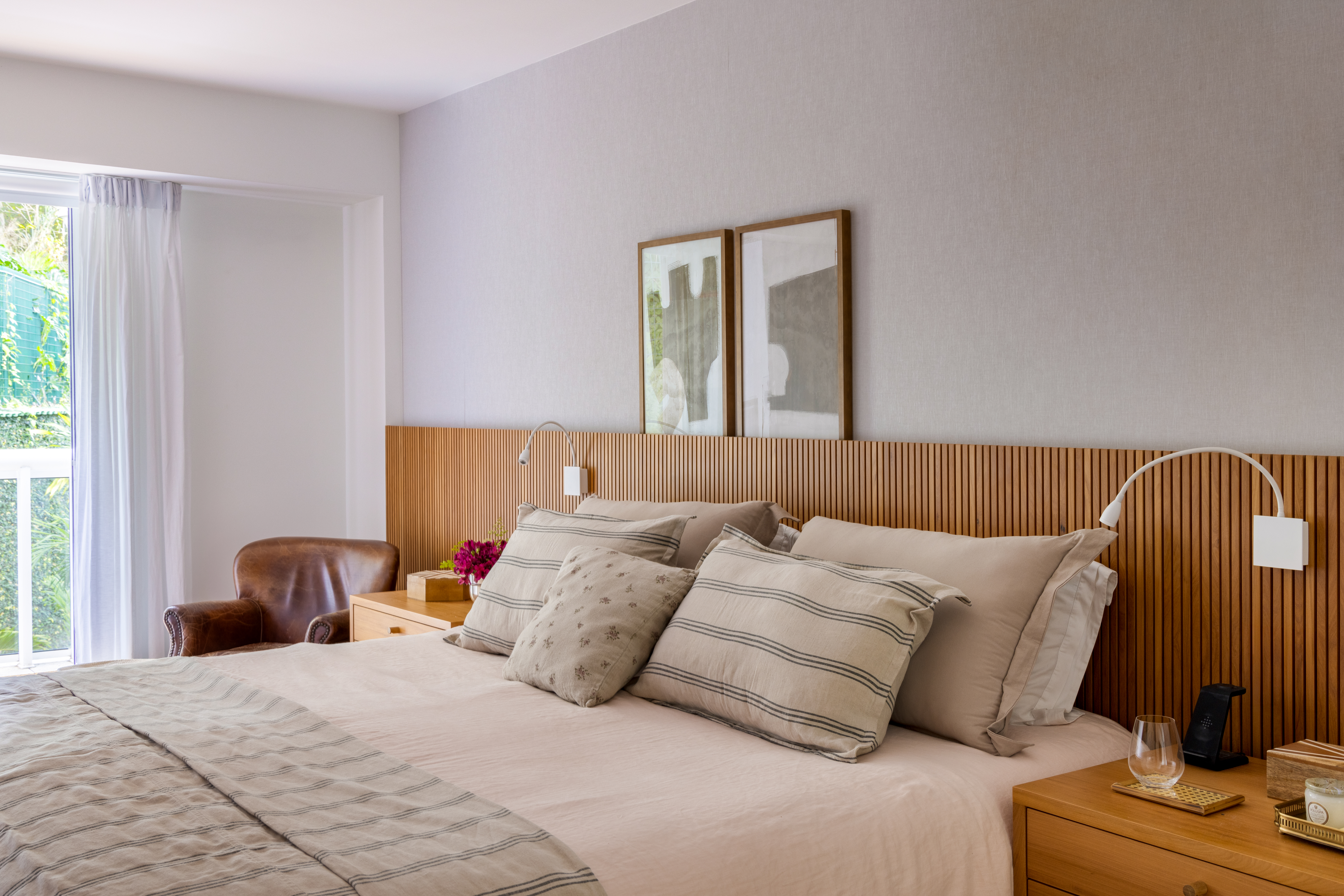 Projeto de Manuela Santos. Na foto, quarto com cama de casal e cabeceira de madeira ripada.