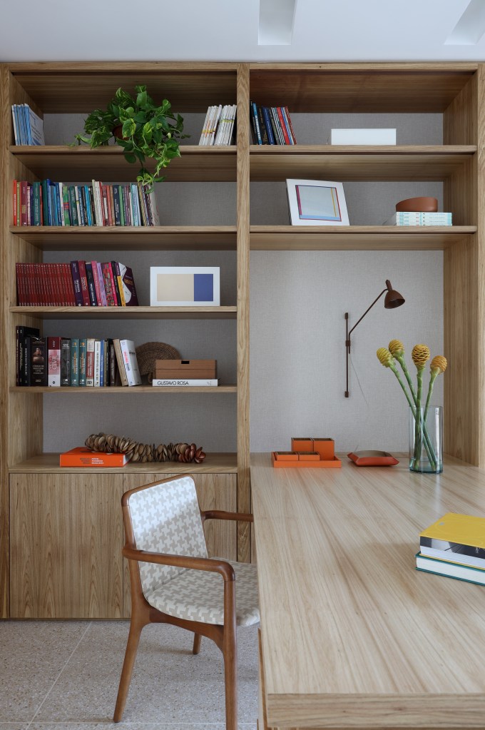 Projeto de Carol Farah. Na foto, home office com estante de marcenaria clara e bancada de madeira.