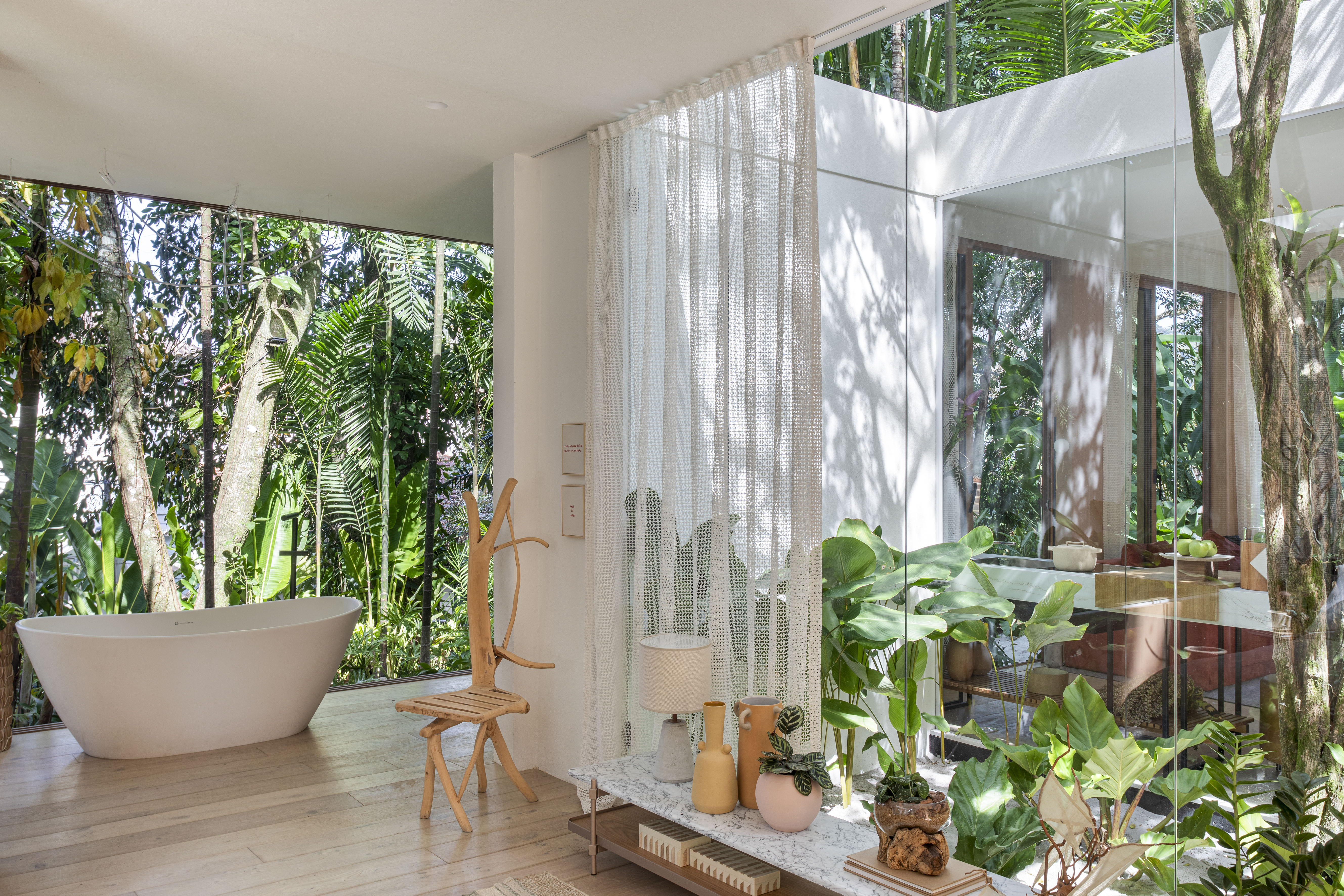 Casa de campo de 105 m² no meio da natureza é feita com três contêineres. Projeto de Up3 Arquitetura para a CASACOR Rio de Janeiro 2023, Na foto, banheiro com banheira, parede de vidro e vista para o jardim.