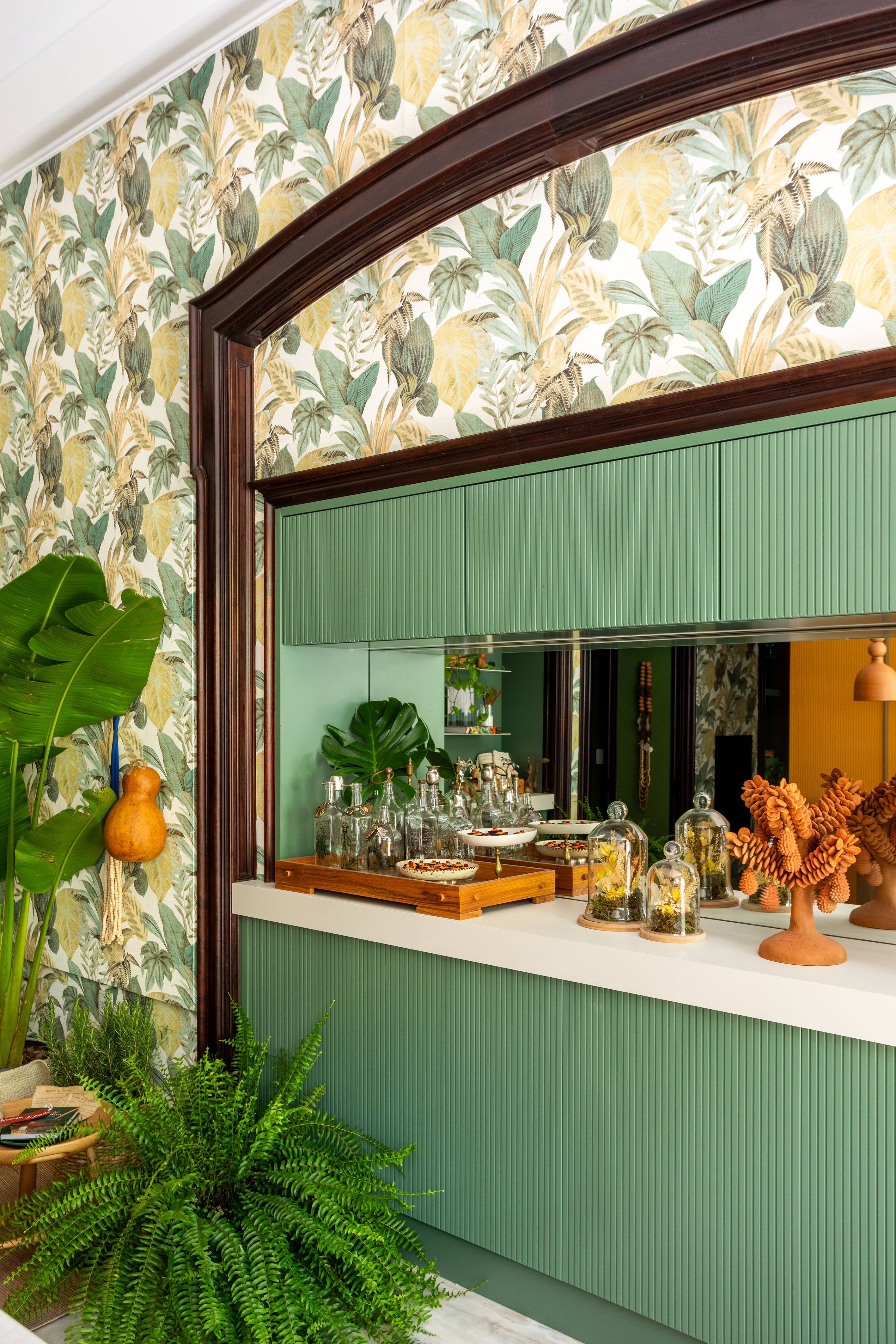 Cozinha com papel de parede de bananeira é repleta de artesanato brasileiro. Projeto de Amanda Miranda para a CASACOR Rio 2023. Na foto, bar da cozinha com marcenaria verde e espelho no backsplash.