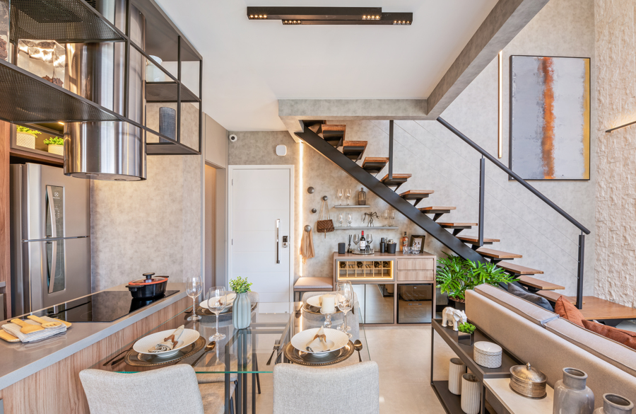 Duplex de 75 m² possui varanda com churrasqueira a carvão e suíte com closet. Na foto, sala de jantar com bar, cozinha acoplada e escada.