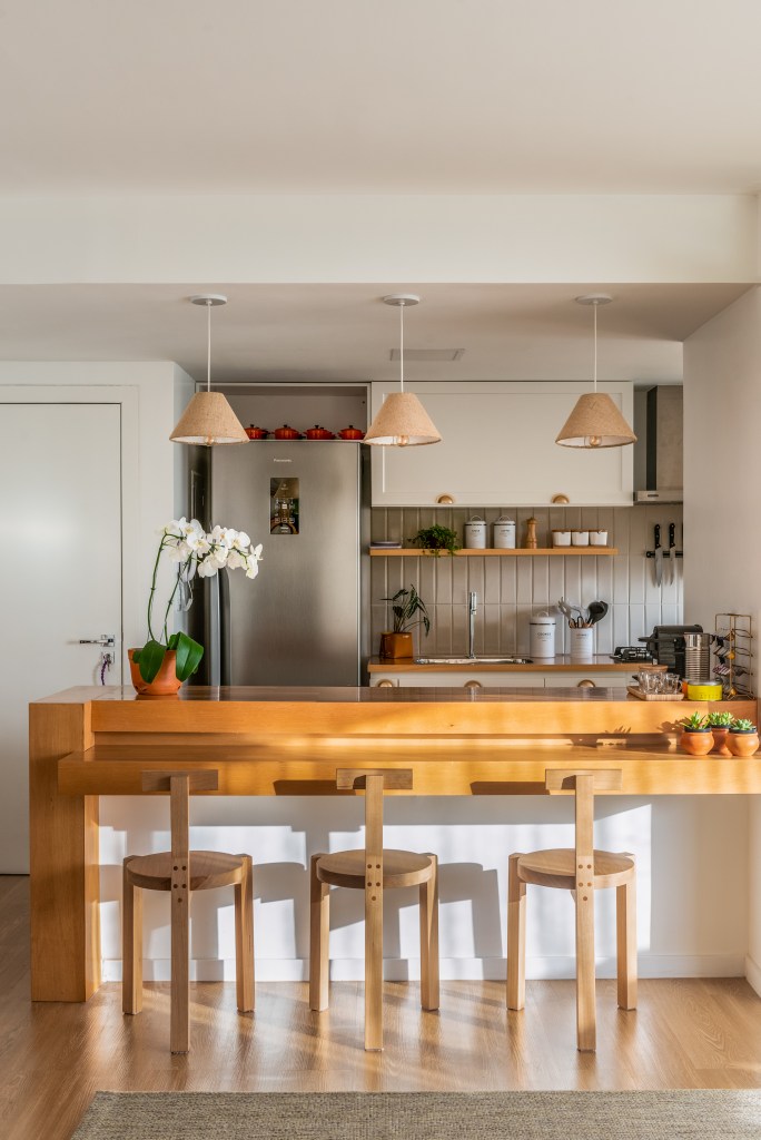 Projeto de Djanira Cabral. Na foto, cozinha integrada com armários em estilo provençal. Bancada de madeira com banquetas.