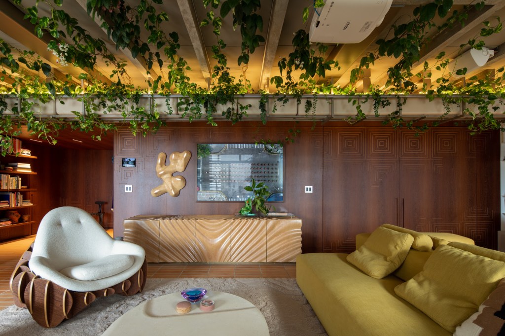 Projeto de Estudio Guto Requena. Na foto, sala de estar com sofá laranja, mesa de centro branca e muitas plantas.