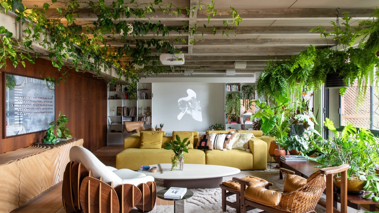 Projeto de Estudio Guto Requena. Na foto, sala de estar com sofá laranja, mesa de centro branca e muitas plantas.