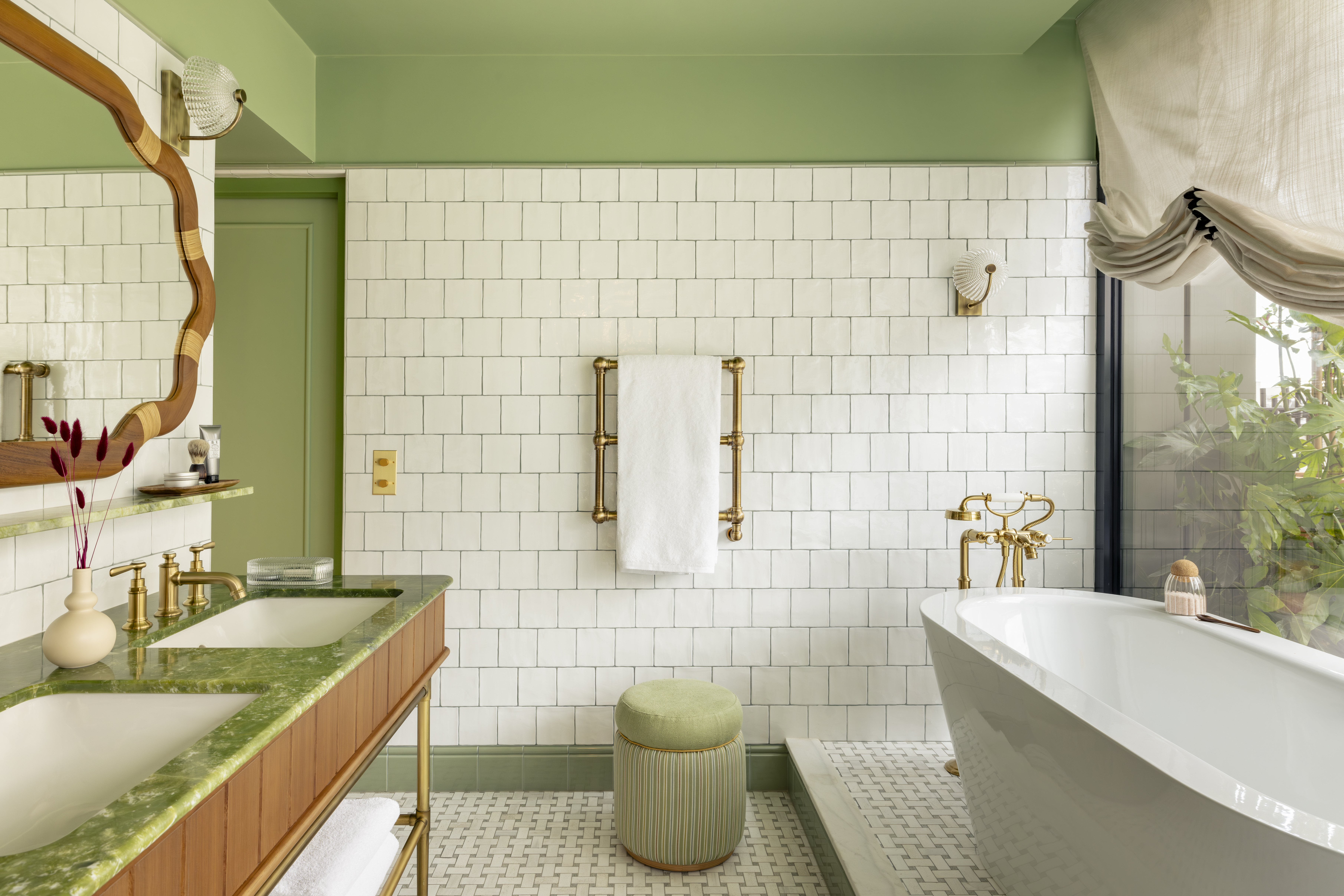 Banheiro com parede verde, parede revestida de ladrilhos brancos e banheira solta.