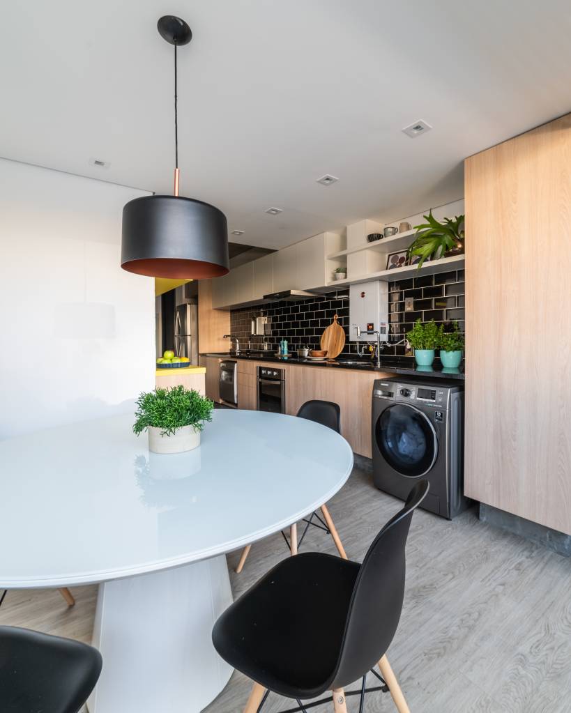 lavanderias-debate-sobre-o-comodo-apartamentos-menores-studio-guadix-03 Projeto de Studio Guadix. Cozinha com prolongamento de bancada preta com máquina de lavar.