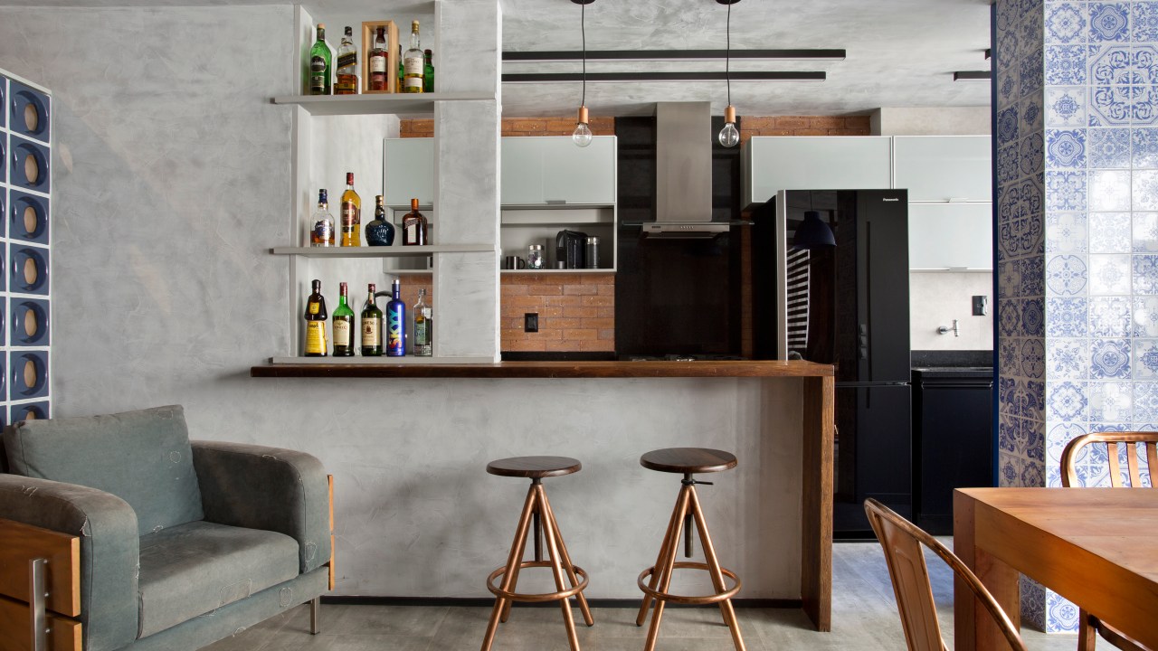 Loft de 70 m² ganha décor industrial inspirado em Nova York. Projeto de Rafael Mirza. Na foto, sala de estar integrada com cozinha, mesa de refeições e parede de cimento queimado.