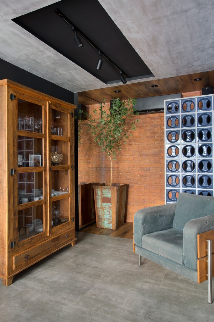 Loft de 70 m² ganha décor industrial inspirado em Nova York. Projeto de Rafael Mirza. Na foto, sala com parede de tijolo aparente, teto de cimento queimado, parede de cobogós.