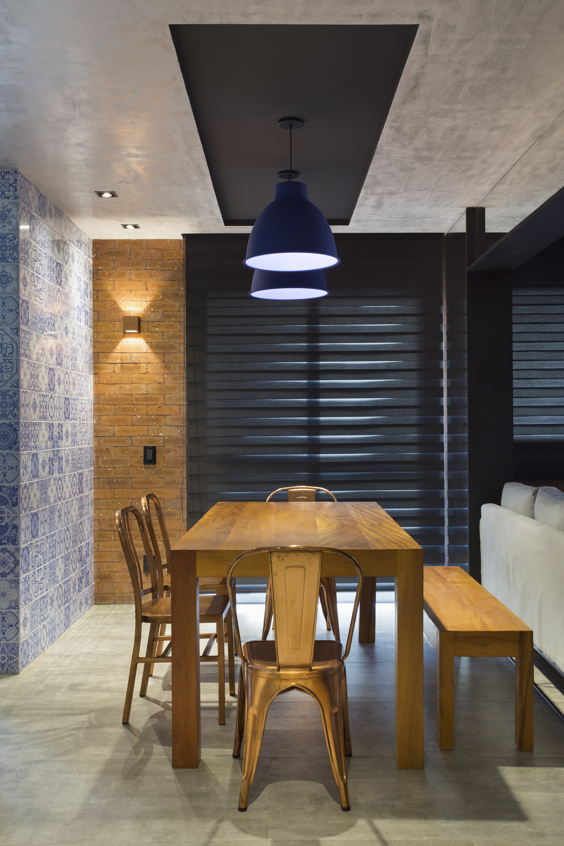 Loft de 70 m² ganha décor industrial inspirado em Nova York. Projeto de Rafael Mirza. Na foto, sala de jantar com mesa, banco e cortina preta.