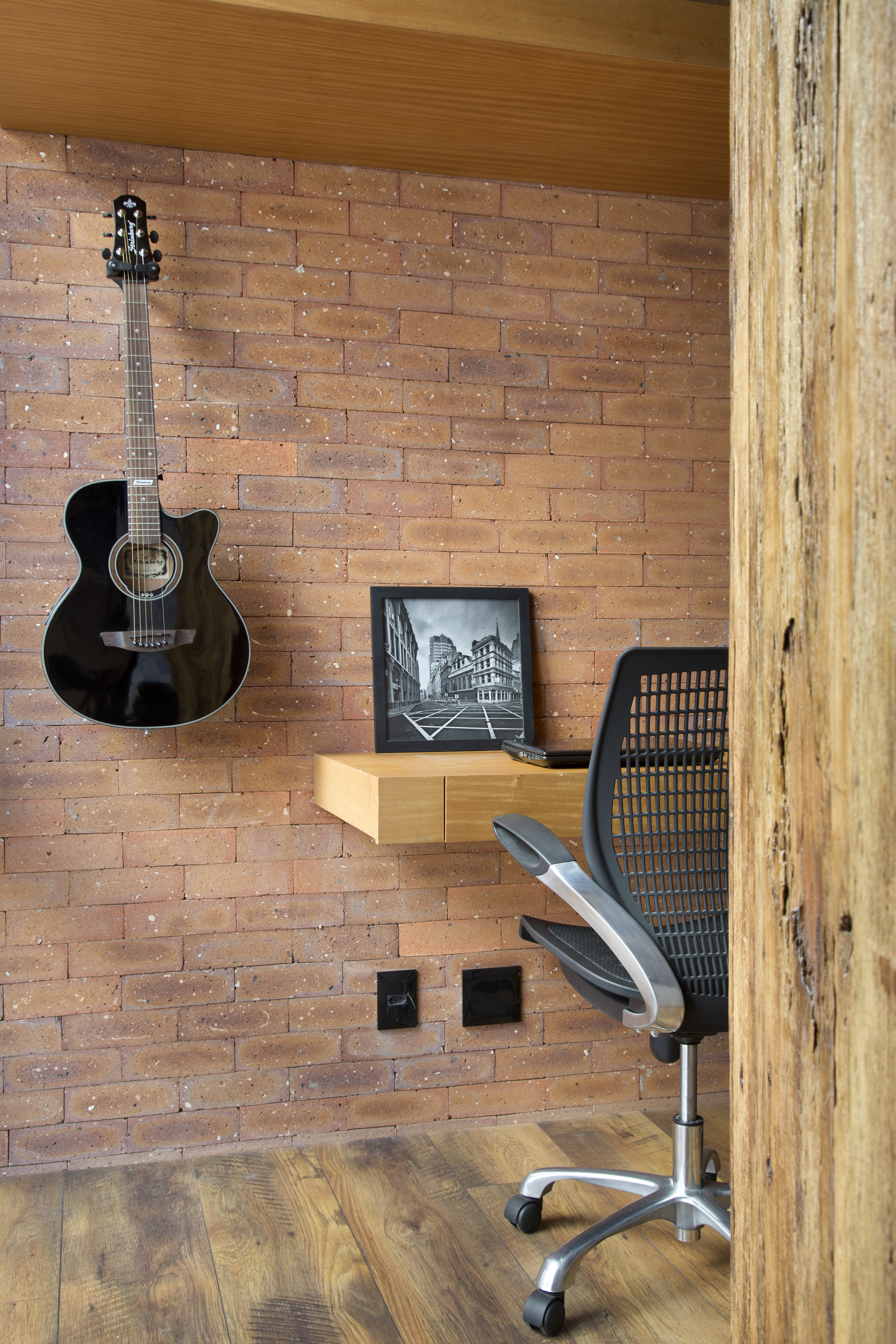 Loft de 70 m² ganha décor industrial inspirado em Nova York. Projeto de Rafael Mirza. Na foto, home office com parede de tijolo aparente.