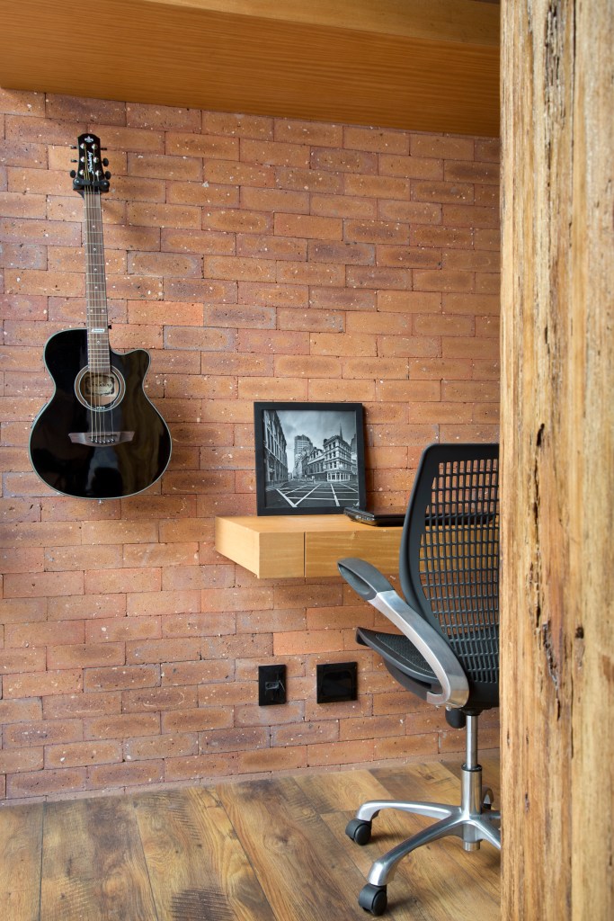 Loft de 70 m² ganha décor industrial inspirado em Nova York. Projeto de Rafael Mirza. Na foto, home office com parede de tijolo aparente.