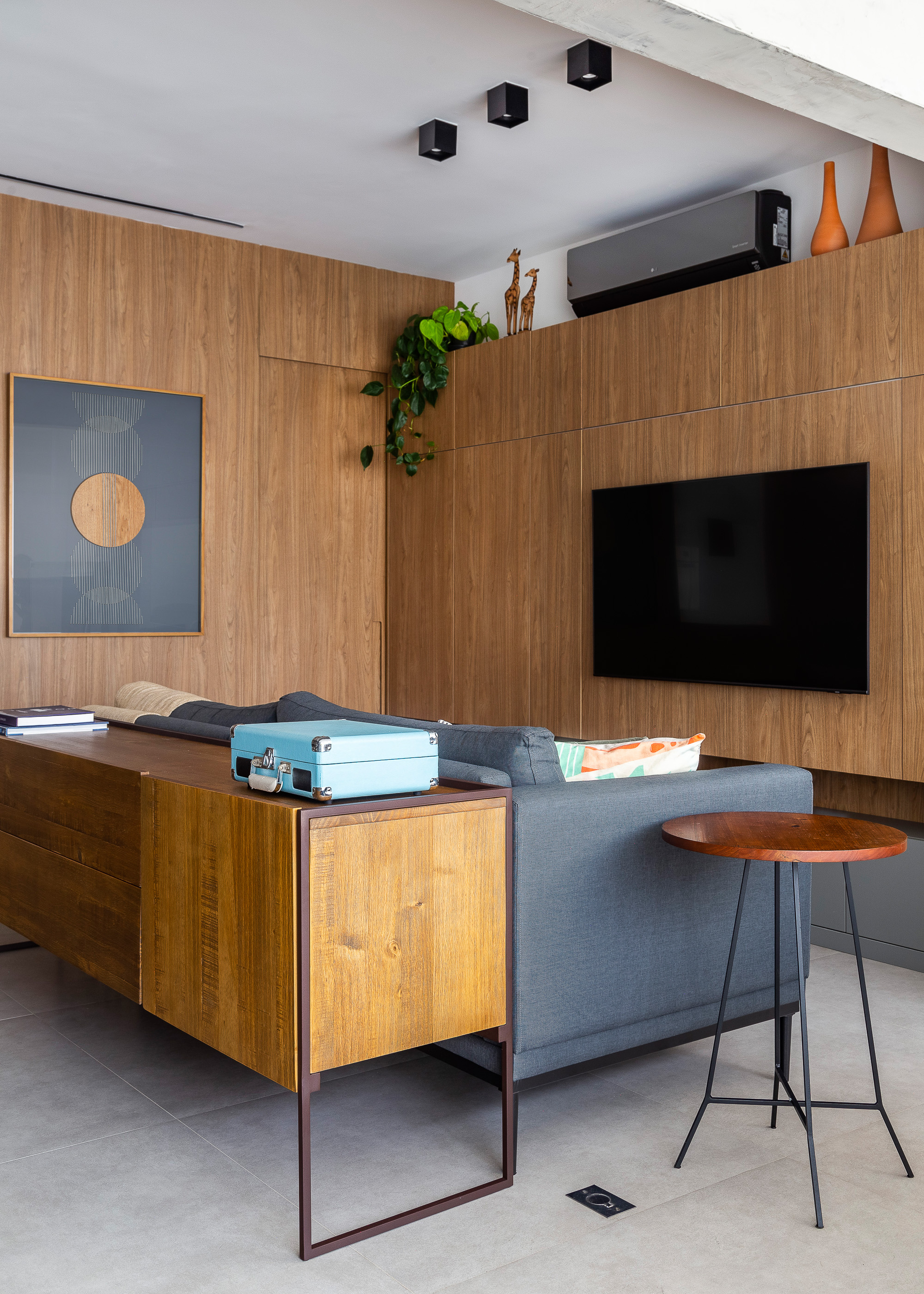 Sala de tv integrada com cozinha e jantar revestida com painéis de madeira