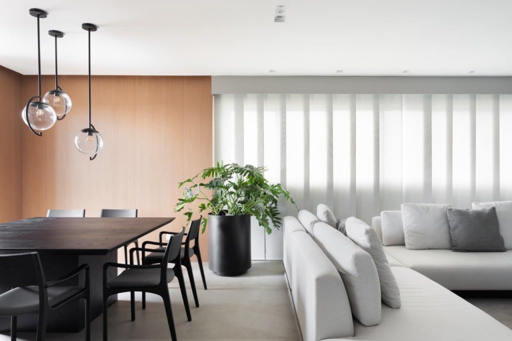 Projeto de archi.lab. Na foto, sala de estar integrada com jantar com mesa de madeira preta e sofá cinza claro.