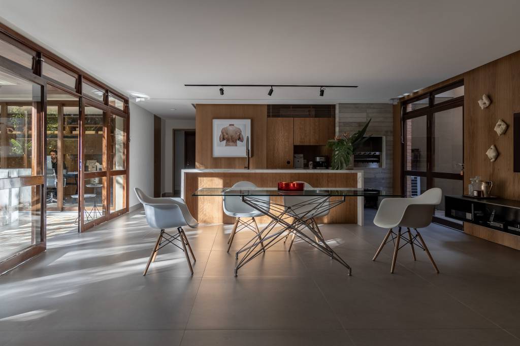 Memorabilia: história de vida do morador se confunde com décor nesta casa. Projeto de Jorge Elmor. Na foto, sala de jantar com mesa de vidro e varanda gourmet.