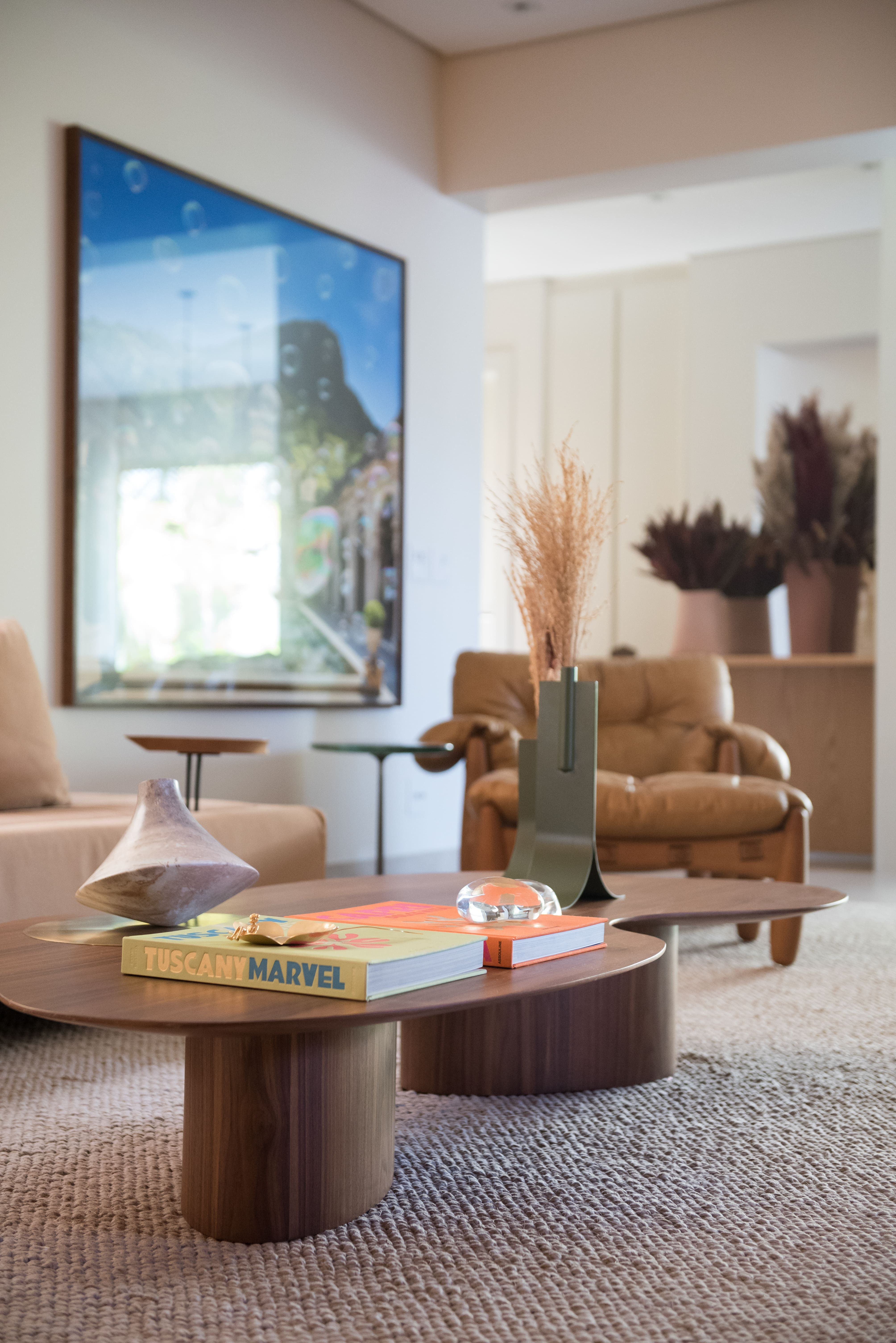 Sala de estar com paleta bege e mesa de centro de madeira com formato orgânico.